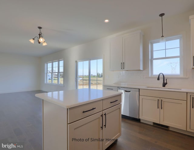 kitchen with decorative light fixtures, light countertops, visible vents, stainless steel dishwasher, and a sink