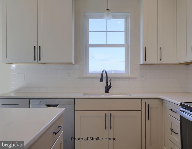 kitchen featuring white cabinets, dishwasher, decorative light fixtures, light countertops, and a sink