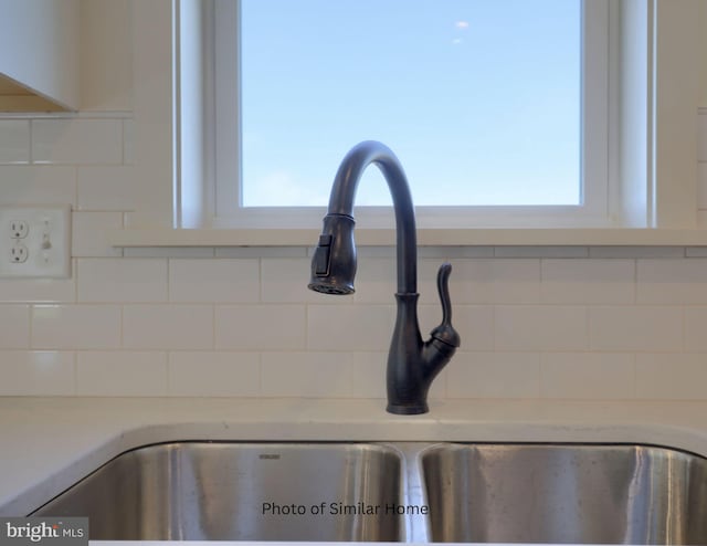 interior details with light countertops, a sink, and backsplash