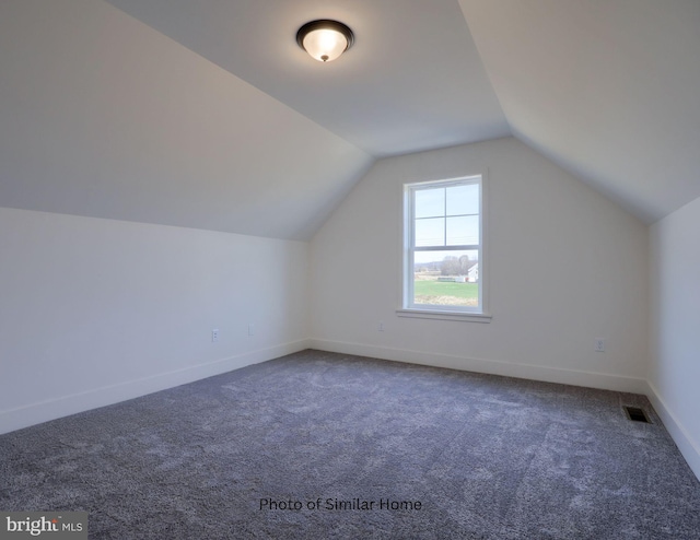 additional living space featuring carpet, visible vents, vaulted ceiling, and baseboards