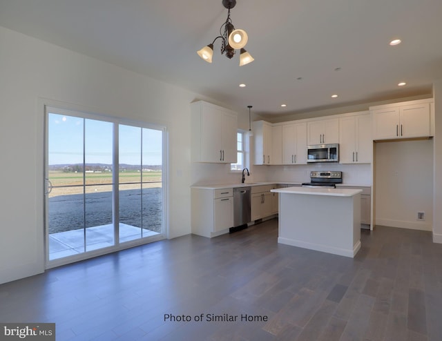 kitchen featuring stainless steel appliances, white cabinetry, dark hardwood / wood-style floors, sink, and a kitchen island