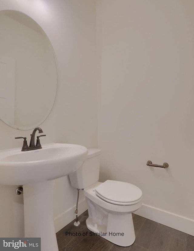 bathroom with baseboards, toilet, and wood finished floors