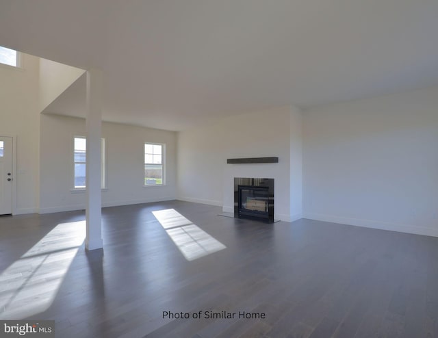 unfurnished living room with a fireplace with flush hearth, baseboards, and dark wood-type flooring