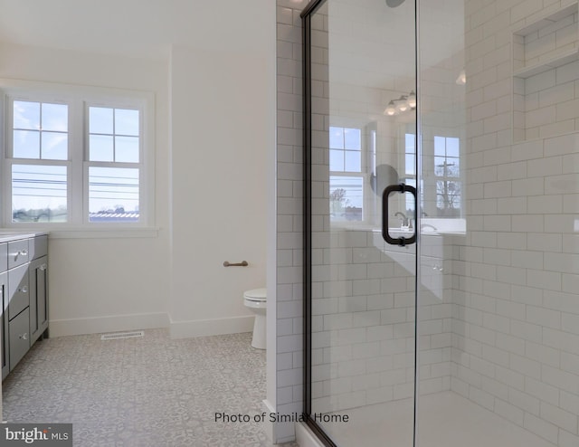 bathroom featuring visible vents, baseboards, toilet, vanity, and a shower stall