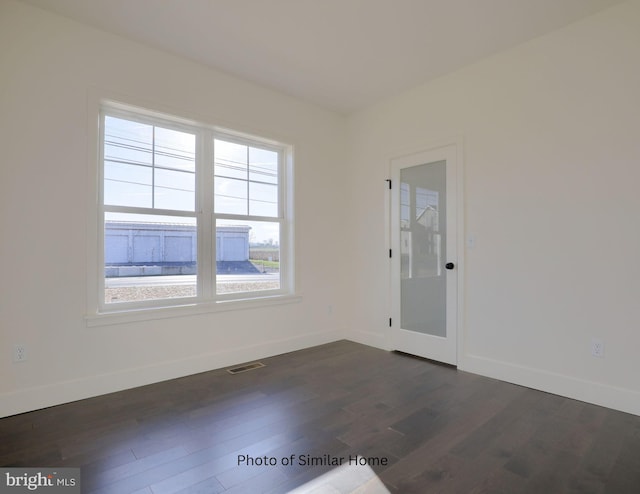 spare room featuring visible vents, dark wood finished floors, and baseboards