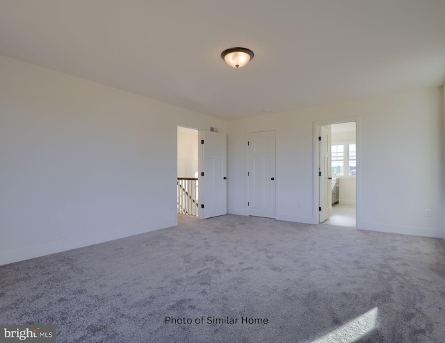 unfurnished bedroom featuring light colored carpet and ensuite bathroom