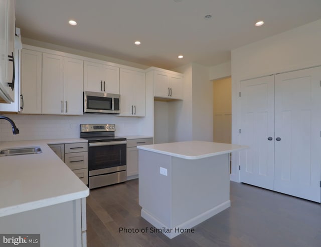 kitchen with white cabinets, a kitchen island, appliances with stainless steel finishes, light countertops, and a sink