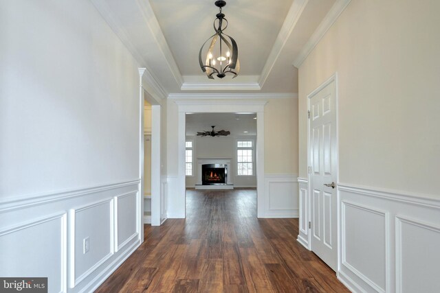 interior space featuring dark hardwood / wood-style floors, a chandelier, ornamental molding, and a tray ceiling