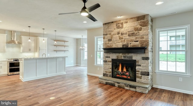 kitchen with stainless steel range oven, wall chimney range hood, plenty of natural light, and light hardwood / wood-style flooring