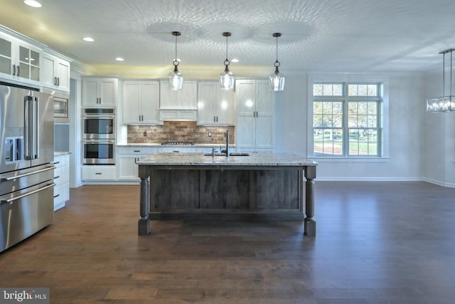 kitchen featuring stainless steel appliances, dark wood-type flooring, hanging light fixtures, and white cabinets