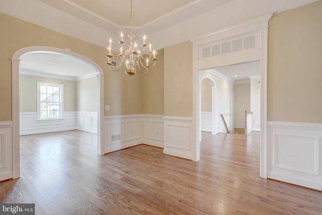 empty room featuring light hardwood / wood-style flooring, a chandelier, and ornamental molding