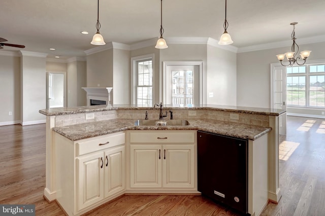 kitchen with sink, ornamental molding, light wood-type flooring, light stone countertops, and dishwasher