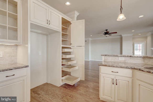 kitchen featuring light wood-type flooring, crown molding, decorative backsplash, and ceiling fan