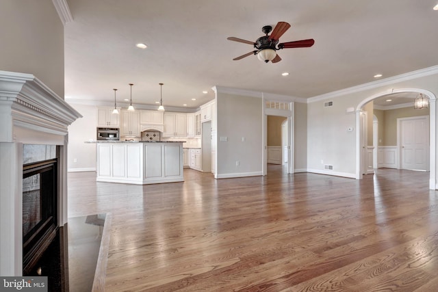 unfurnished living room featuring ceiling fan, light hardwood / wood-style floors, ornamental molding, and a premium fireplace