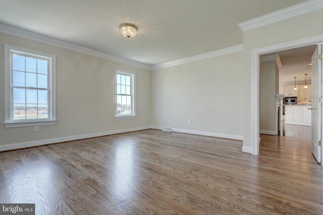 spare room with ornamental molding, a healthy amount of sunlight, and wood-type flooring