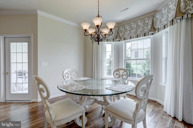 dining area with a wealth of natural light, light hardwood / wood-style floors, a chandelier, and ornamental molding