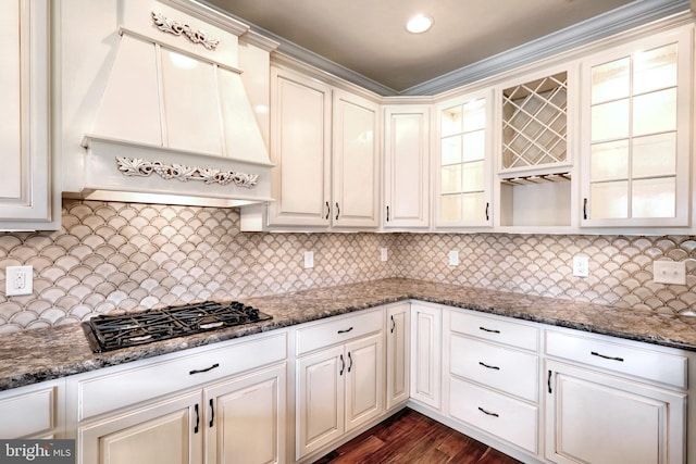 kitchen with dark hardwood / wood-style floors, dark stone countertops, custom exhaust hood, and decorative backsplash