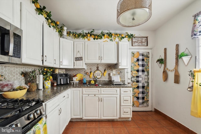 kitchen with dark stone countertops, light tile patterned floors, decorative backsplash, and white cabinets