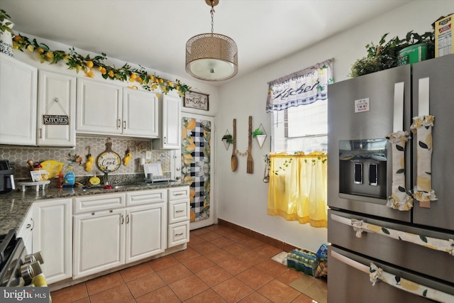 kitchen featuring tile patterned floors, decorative backsplash, stainless steel fridge, and dark stone counters