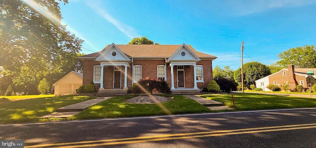 view of front of house with an outbuilding, a garage, and a front lawn