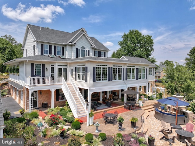 rear view of property with brick siding, outdoor lounge area, an attached garage, a patio area, and driveway