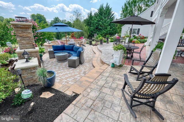 view of patio / terrace with outdoor dining space and an outdoor living space with a fireplace