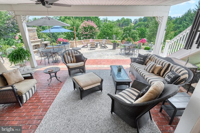 view of patio / terrace featuring outdoor dining space, ceiling fan, and an outdoor living space with a fireplace