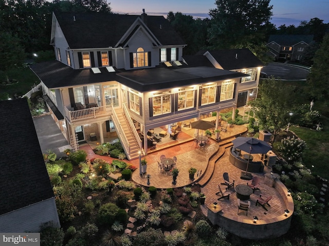 back of property at dusk featuring a fire pit, a patio area, stairway, and outdoor dining space