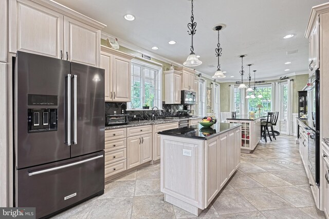 kitchen featuring tasteful backsplash, appliances with stainless steel finishes, ornamental molding, a center island, and hanging light fixtures