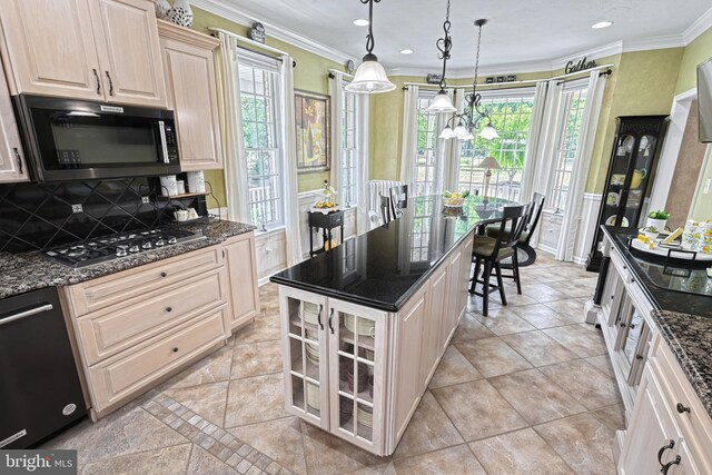 kitchen featuring stainless steel gas cooktop, hanging light fixtures, ornamental molding, dark stone counters, and plenty of natural light