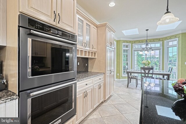 kitchen with tasteful backsplash, dark stone counters, glass insert cabinets, hanging light fixtures, and stainless steel double oven