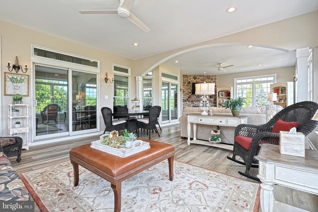 living area with arched walkways, light wood-type flooring, a ceiling fan, and recessed lighting