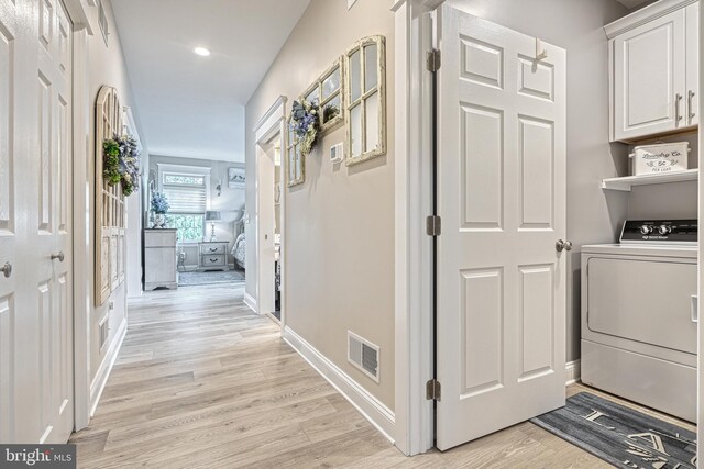 laundry room featuring visible vents, baseboards, light wood-style floors, cabinet space, and washer / dryer