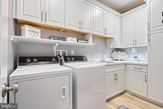 laundry room with light wood-type flooring, cabinet space, independent washer and dryer, and a sink