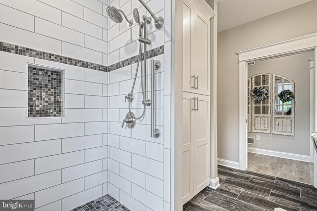 full bathroom with wood tiled floor, tiled shower, and baseboards