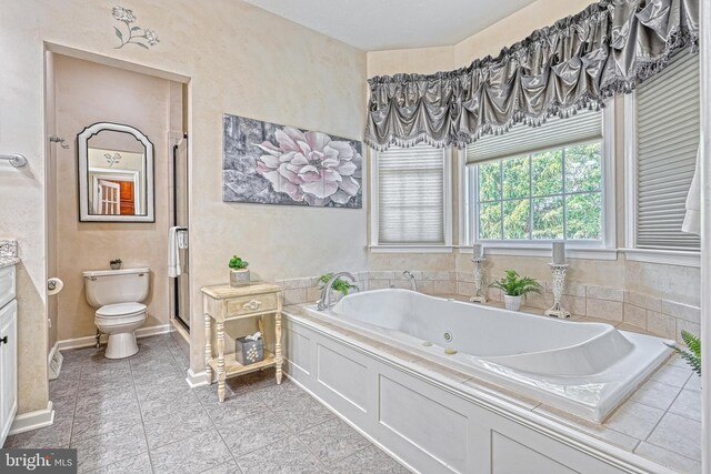 full bathroom with baseboards, toilet, tile patterned floors, vanity, and a bath