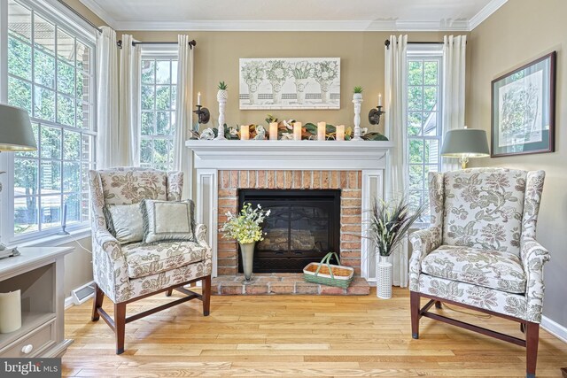 living area featuring a fireplace, crown molding, visible vents, wood finished floors, and baseboards