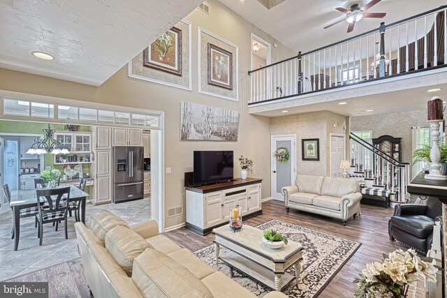 living area featuring visible vents, stairway, ceiling fan, wood finished floors, and baseboards