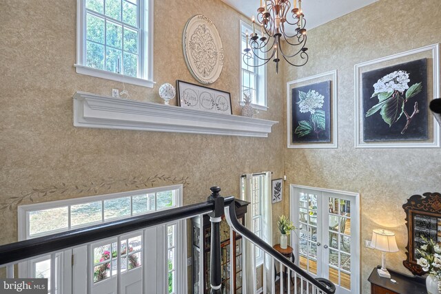 interior details featuring a chandelier, french doors, and wallpapered walls