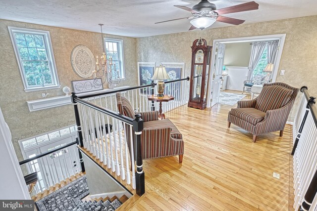 sitting room with plenty of natural light, wood finished floors, and an upstairs landing