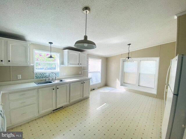 kitchen with white cabinets, plenty of natural light, sink, lofted ceiling, and white fridge