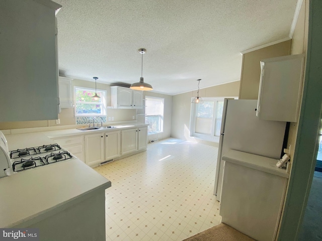 kitchen featuring hanging light fixtures, sink, white cabinetry, and vaulted ceiling