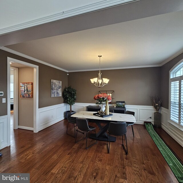 dining area with ornamental molding, dark wood-type flooring, and an inviting chandelier