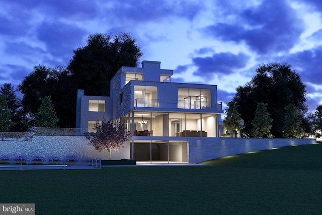 back house at dusk with a lawn and a balcony