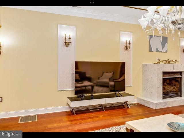 sitting room featuring a fireplace, a notable chandelier, crown molding, and wood-type flooring