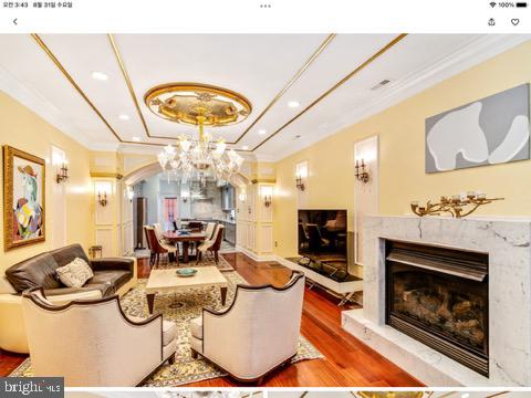 living room with crown molding, a tray ceiling, a high end fireplace, and hardwood / wood-style floors