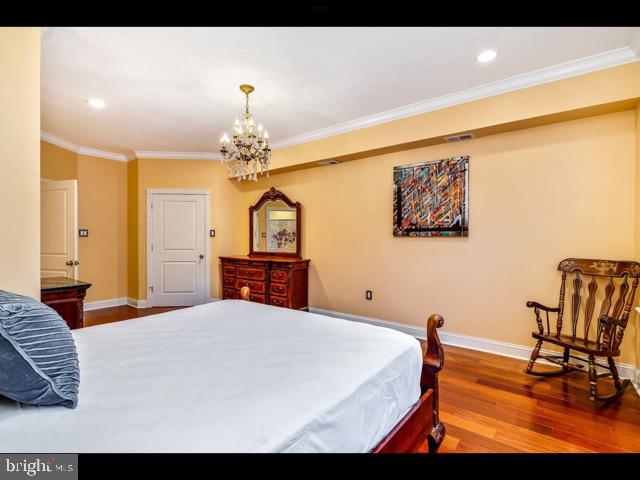 bedroom with hardwood / wood-style floors, crown molding, and a chandelier