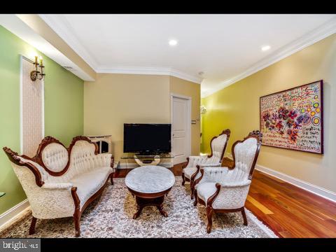 living area featuring hardwood / wood-style floors and crown molding