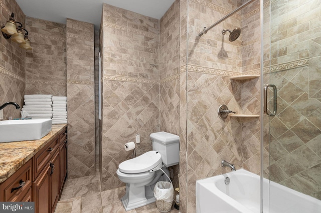 full bathroom with toilet, combined bath / shower with glass door, tile walls, and vanity