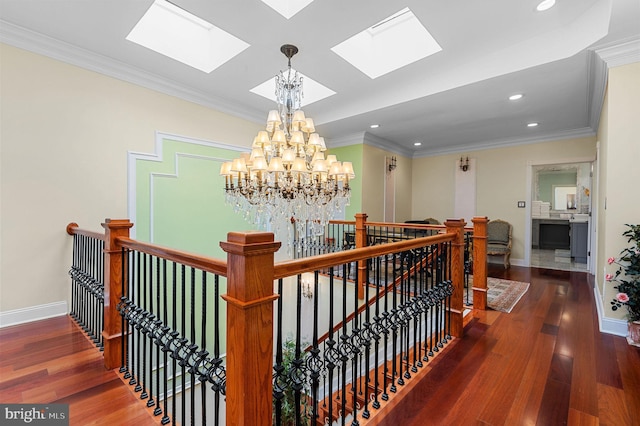 corridor with dark wood-style floors, baseboards, ornamental molding, and an upstairs landing